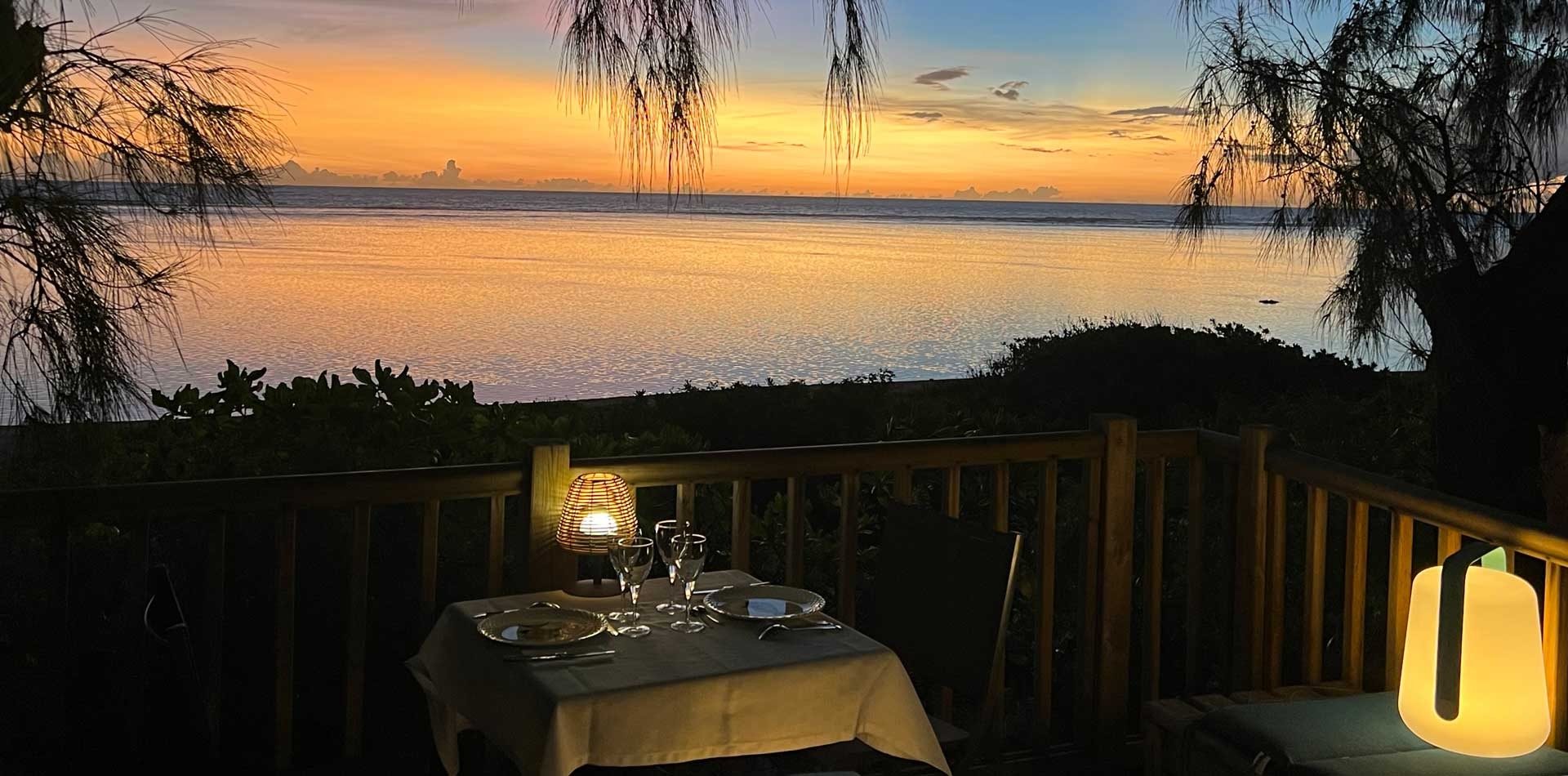 Table dressée pour un dîner en amoureux sur la terrasse dans les arbres, au coucher du soleil sur le lagon