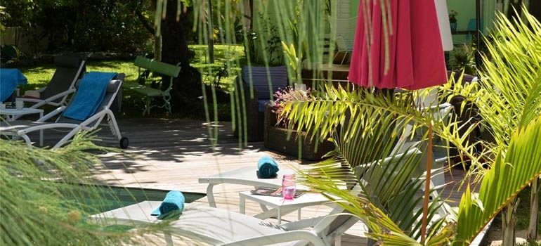 Transats et parasol autour de la piscine, à l'ombre des palmiers