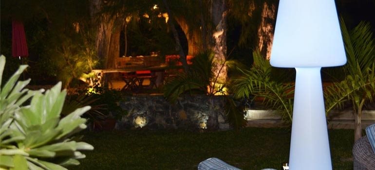 Jardin tropical illuminé la nuit, table sous les arbres
