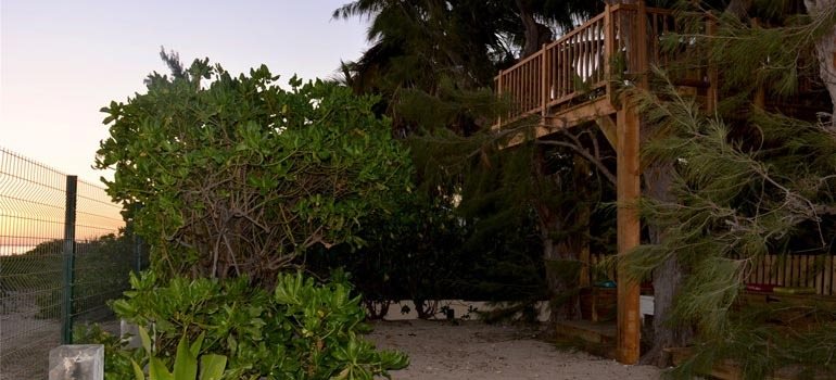 Allée de sable menant à la plage, au pied de la terrasse dans les arbres