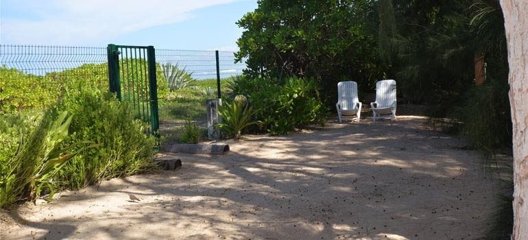 Coin détente côté plage avec deux fauteuils et le portillon d'accès à la mer