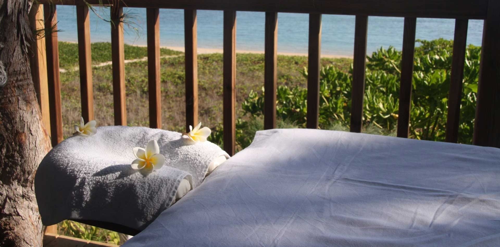 Table de massage installée sur la terrasse dans les arbres, avec vue sur la plage et le lagon