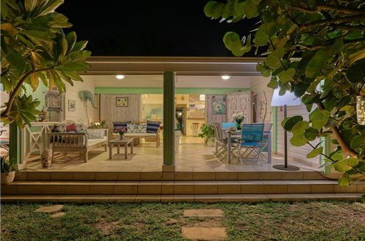 Terrasse couverte et salon de la maison éclairés à la tombée de la nuit