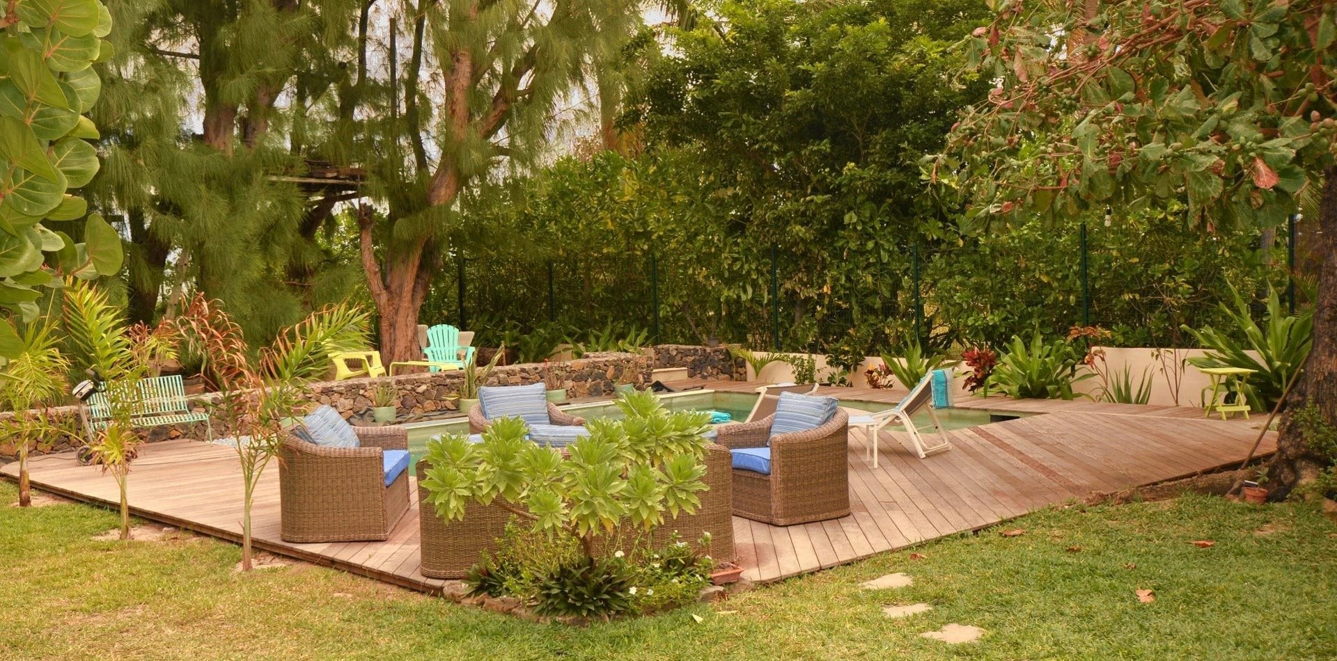 Salon de jardin sur un deck en bois au milieu du jardin tropical de la villa
