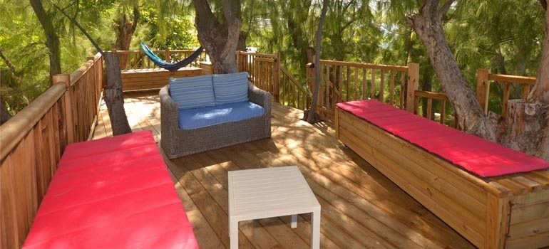 Terrasse dans les arbres aménagée avec banquettes, canapé et hamac