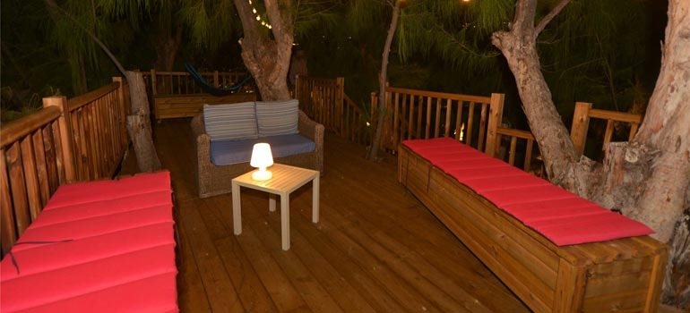 Terrasse dans les arbres éclairée le soir par une lampe