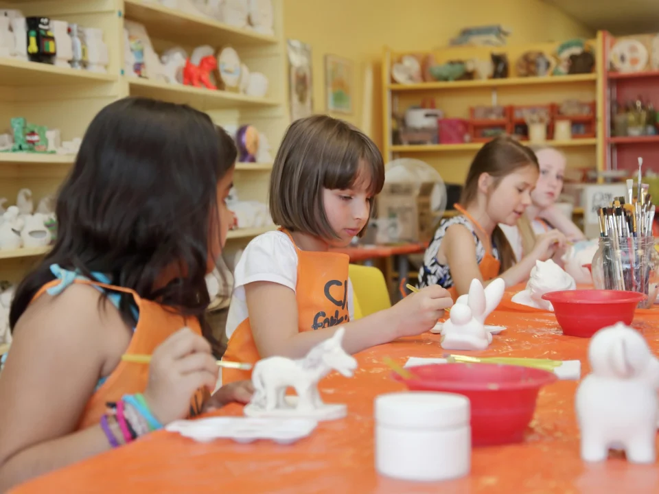 Enfants en tablier peignant des figurines en céramique pendant un anniversaire à Saint-Pierre