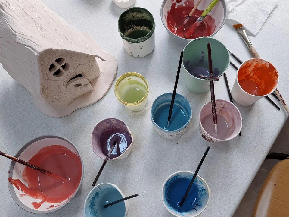 Pots de peinture colorés et pinceaux prêts pour un atelier de peinture sur céramique