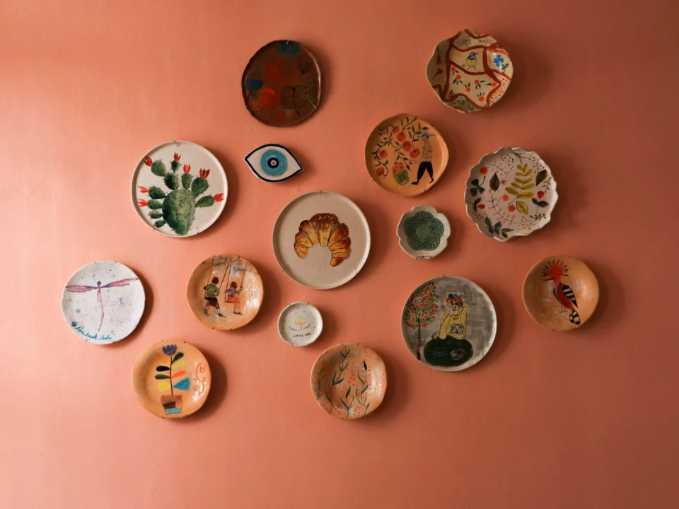 Assiettes et coupelles en céramique peintes à la main sur un mur orange corail